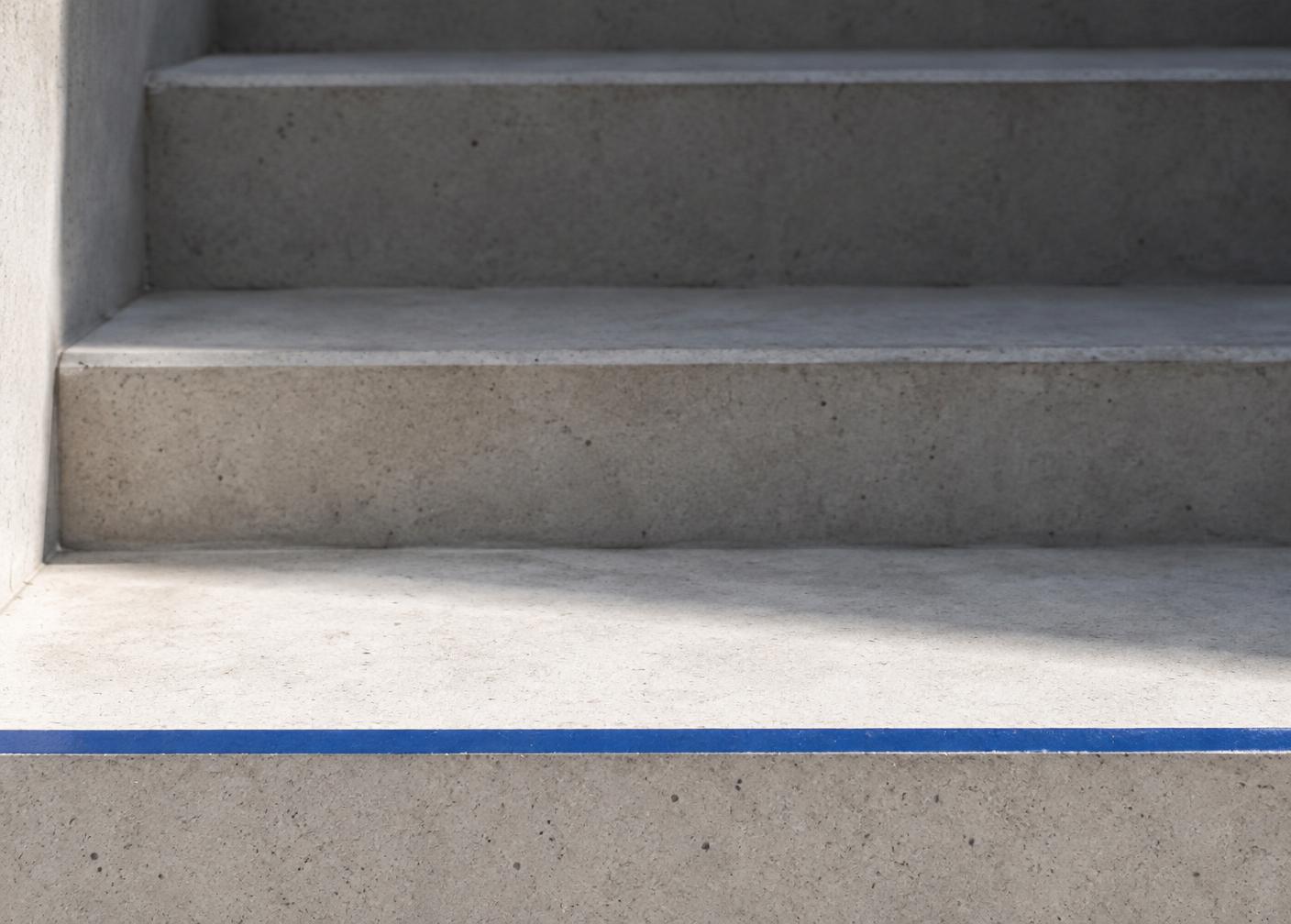 Three concrete steps, the lowest one lit and marked with a blue line